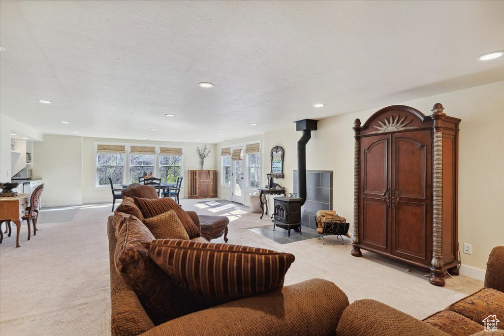 Living room featuring light colored carpet, recessed lighting, a wood stove, and baseboards