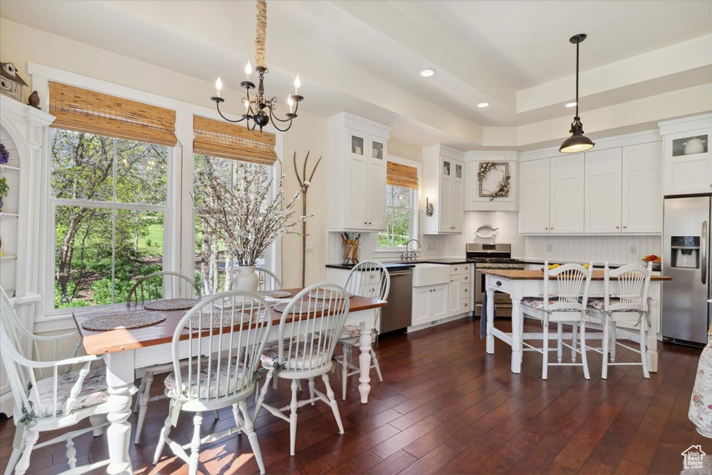 Kitchen with stainless steel appliances, a chandelier, white cabinets, recessed lighting, and glass insert cabinets