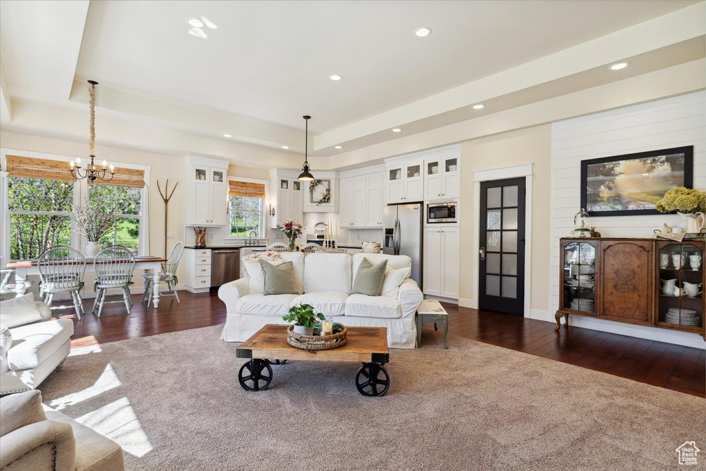 Living area with a chandelier, dark wood finished floors, a tray ceiling, and recessed lighting
