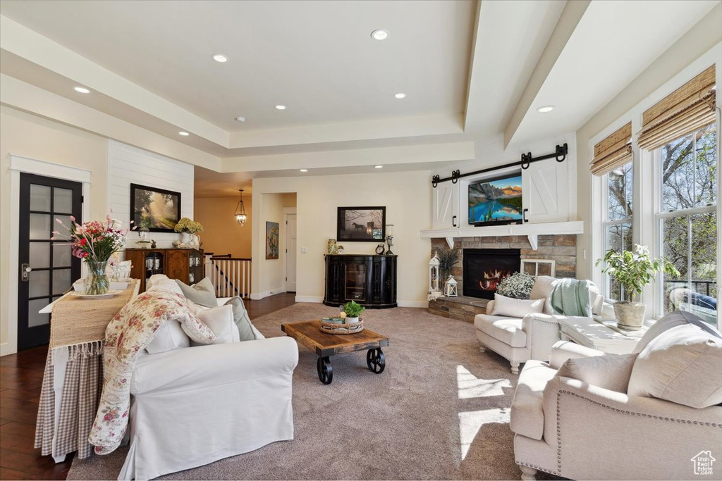 Living area featuring a raised ceiling, recessed lighting, a fireplace, and baseboards