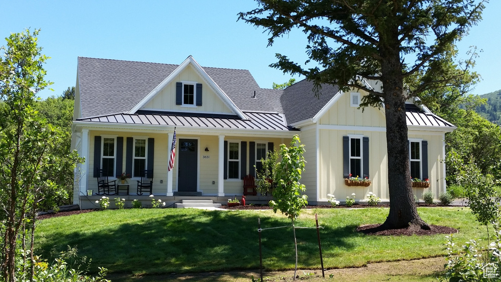 Modern farmhouse style home with a standing seam roof, covered porch, and a front lawn