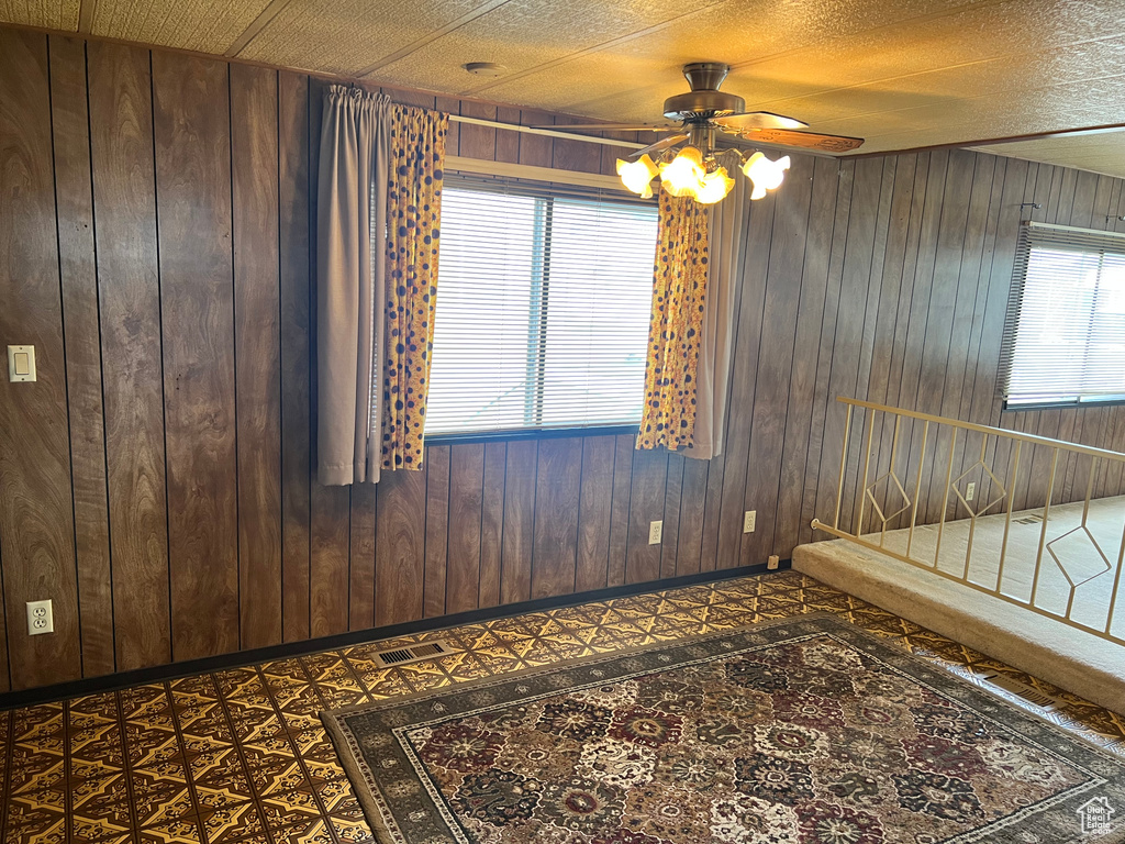 Unfurnished room with ceiling fan, wooden walls, and baseboards