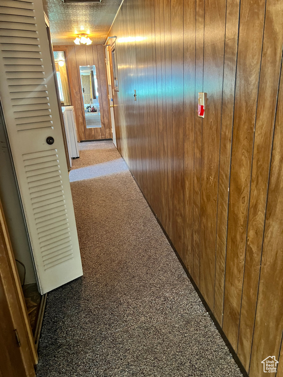 Corridor featuring wood walls and carpet flooring