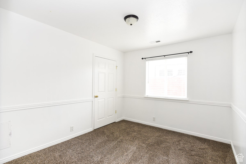 Unfurnished room featuring dark carpet and baseboards
