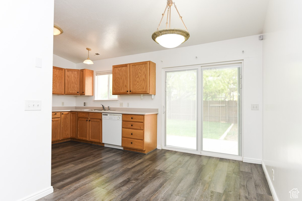 Kitchen featuring white dishwasher, dark wood-style floors, light countertops, lofted ceiling, and a sink