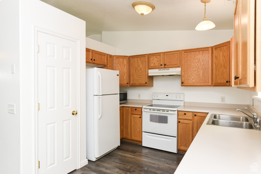 Kitchen featuring white appliances, under cabinet range hood, vaulted ceiling, a sink, and dark wood-type flooring