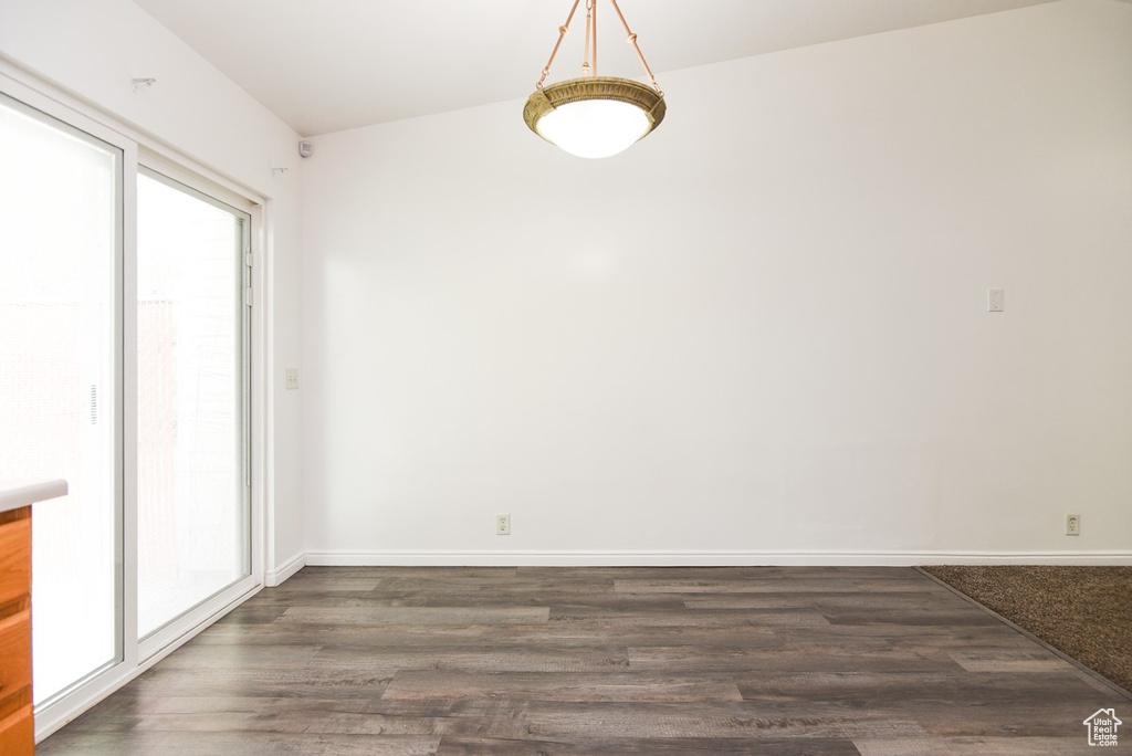 Unfurnished dining area with dark wood-style floors and baseboards