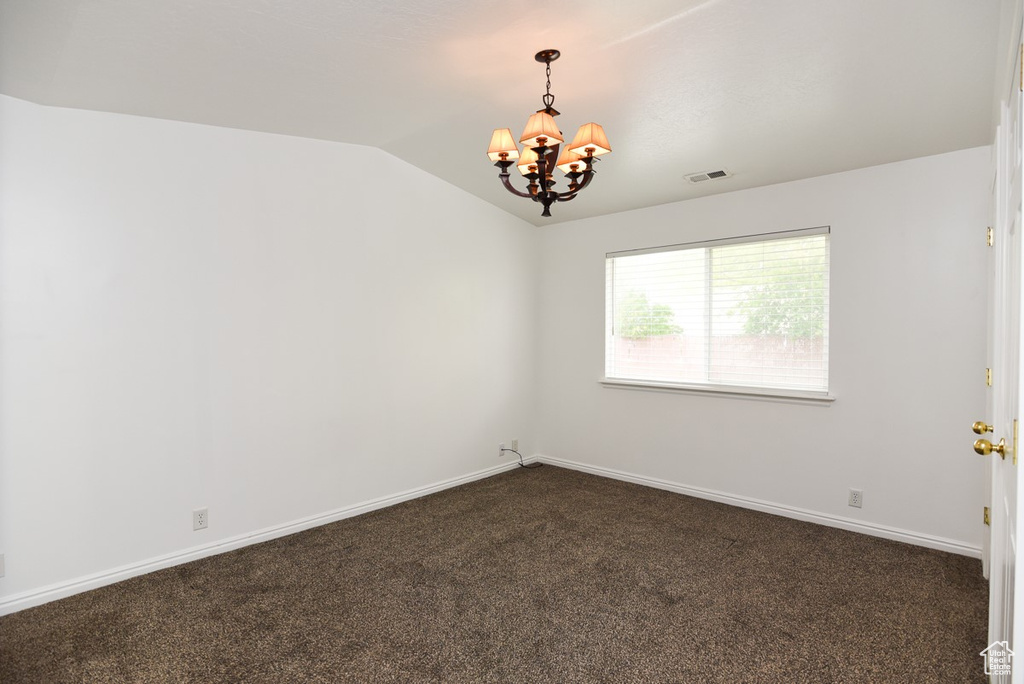 Unfurnished room with a chandelier, vaulted ceiling, dark carpet, and baseboards