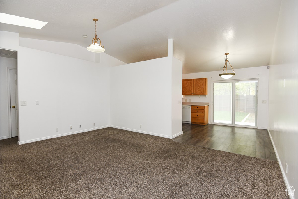 Unfurnished living room with dark carpet, vaulted ceiling, a skylight, and baseboards