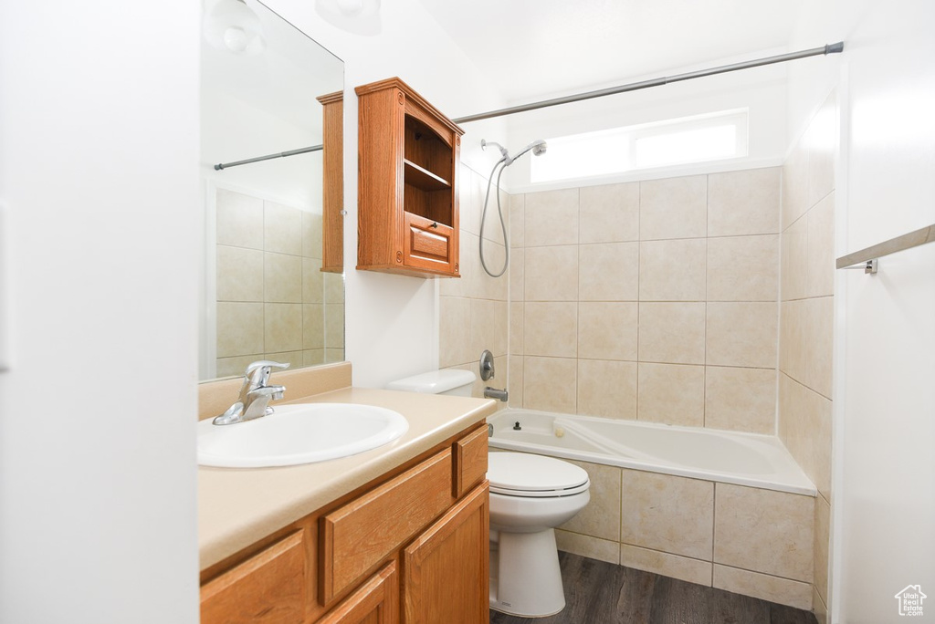 Full bathroom with toilet, vanity, tiled shower / bath, and wood finished floors