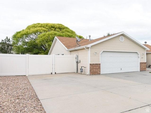Ranch-style house featuring brick siding, concrete driveway, a garage, and a gate