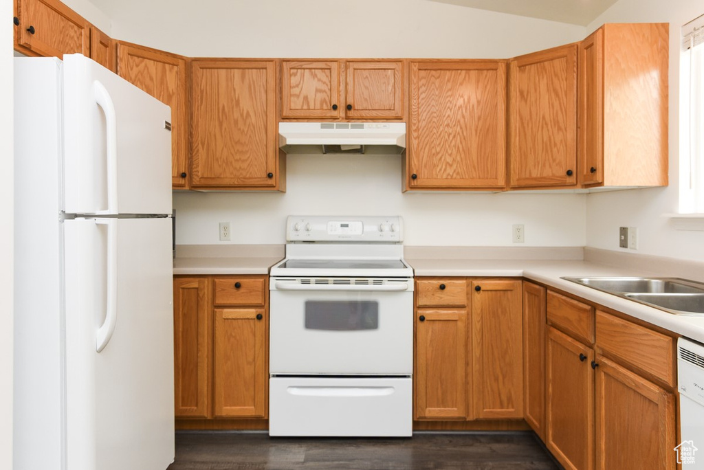 Kitchen with white appliances, under cabinet range hood, light countertops, and dark wood-style flooring