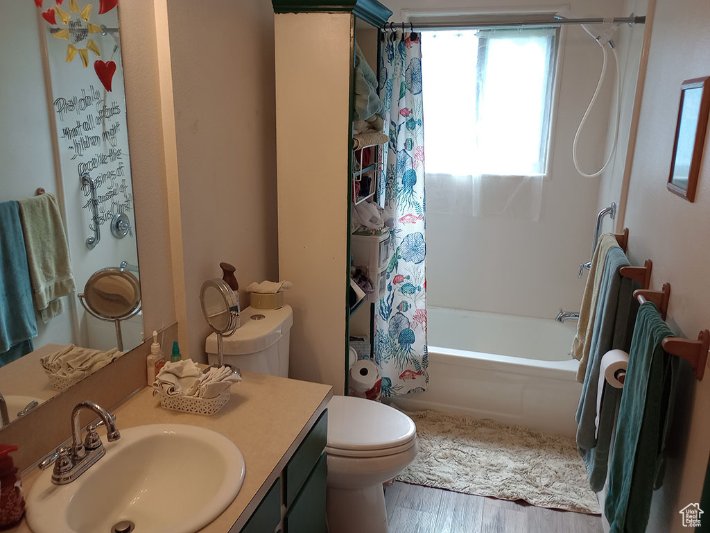 Full bathroom featuring toilet, shower / bath combo, vanity, and wood finished floors