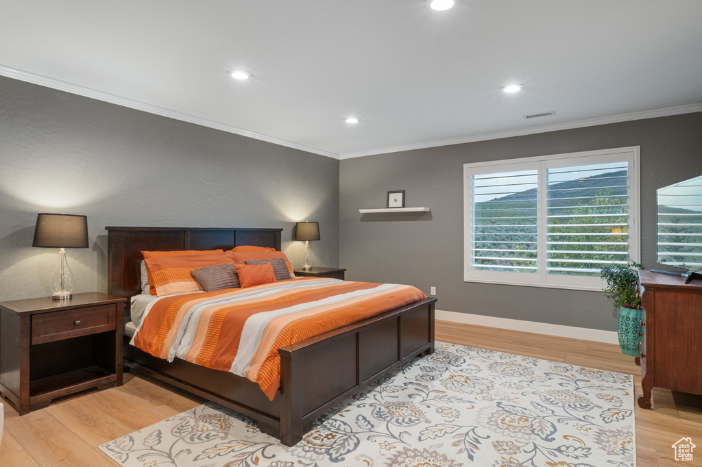 Bedroom with crown molding, light wood finished floors, recessed lighting, and baseboards