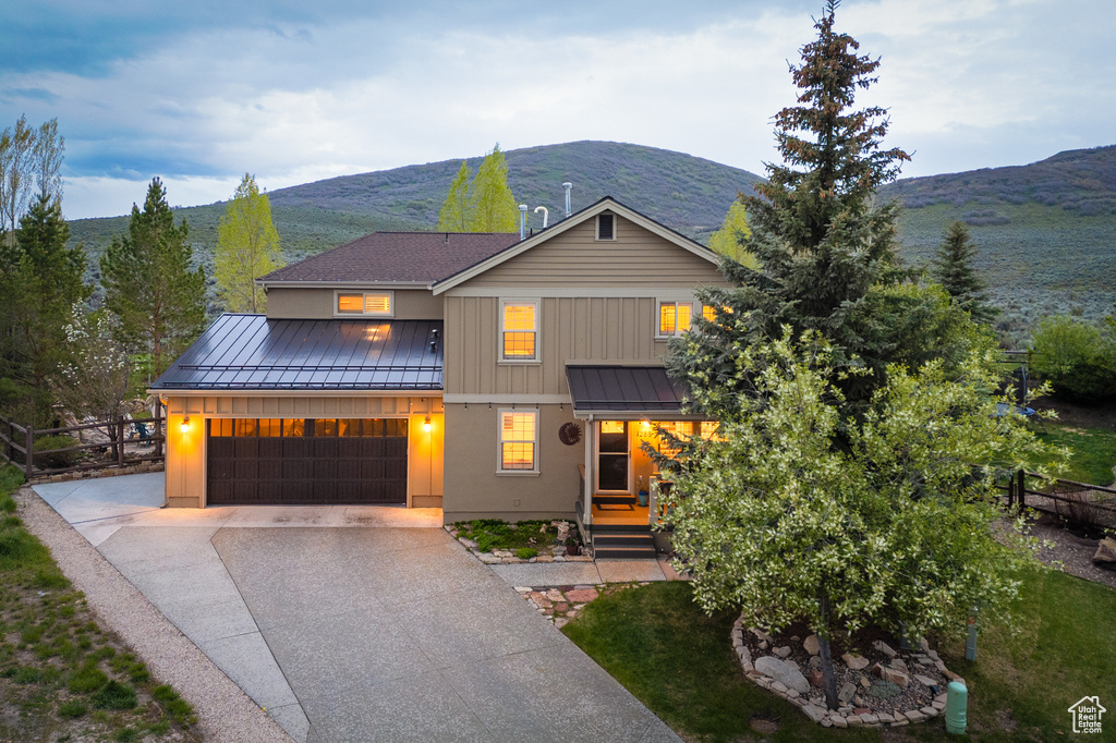 View of front of home featuring a standing seam roof, metal roof, concrete driveway, a mountain view, and an attached garage