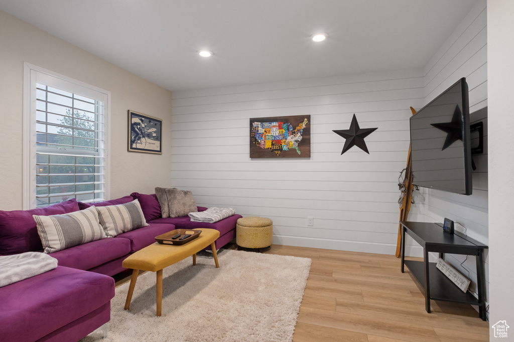 Living room with light wood-style flooring, recessed lighting, baseboards, and wood walls