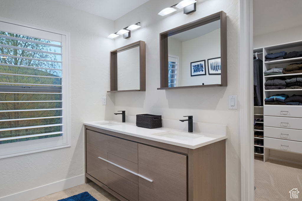 Bathroom with a walk in closet, double vanity, and baseboards