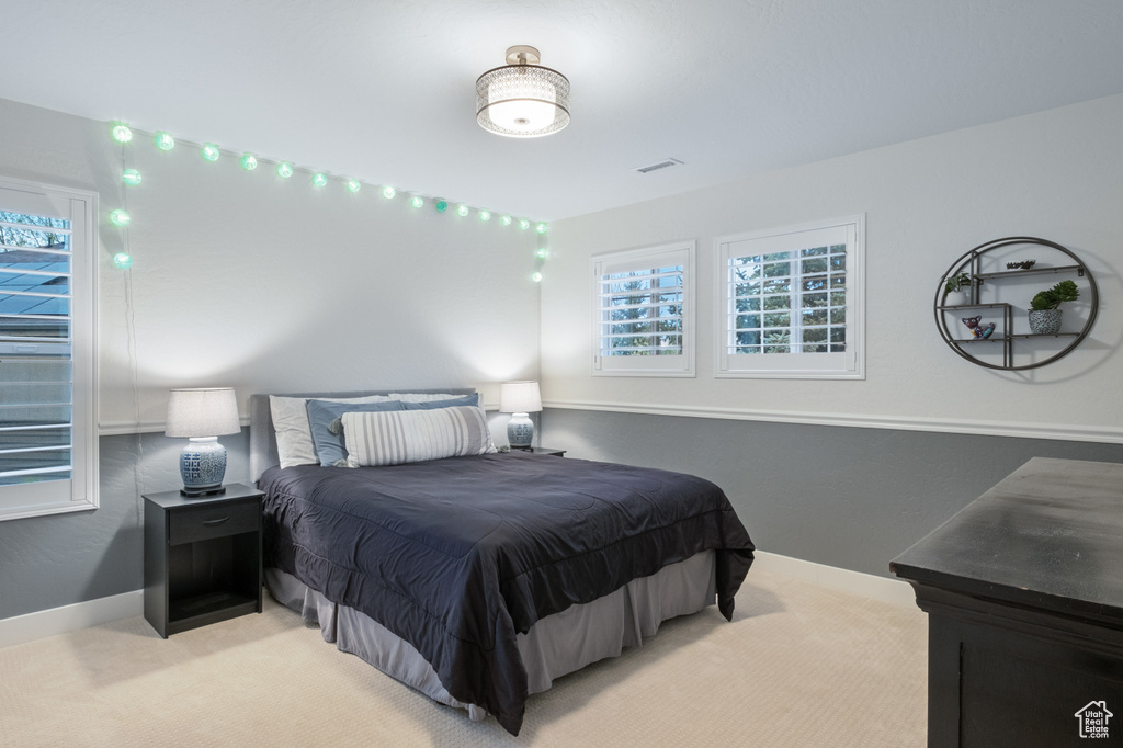 Bedroom featuring light colored carpet, multiple windows, and baseboards