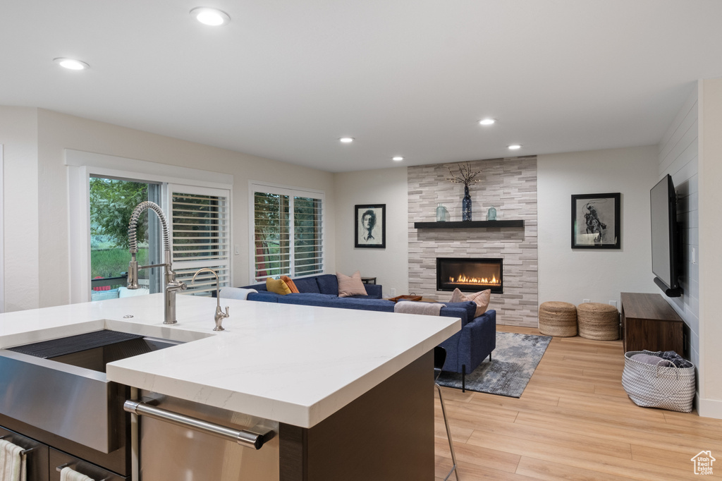 Kitchen featuring light wood-style flooring, a sink, light countertops, recessed lighting, and a tile fireplace