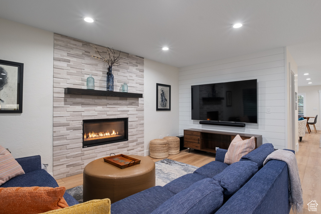 Living room with wood finished floors, recessed lighting, and a stone fireplace