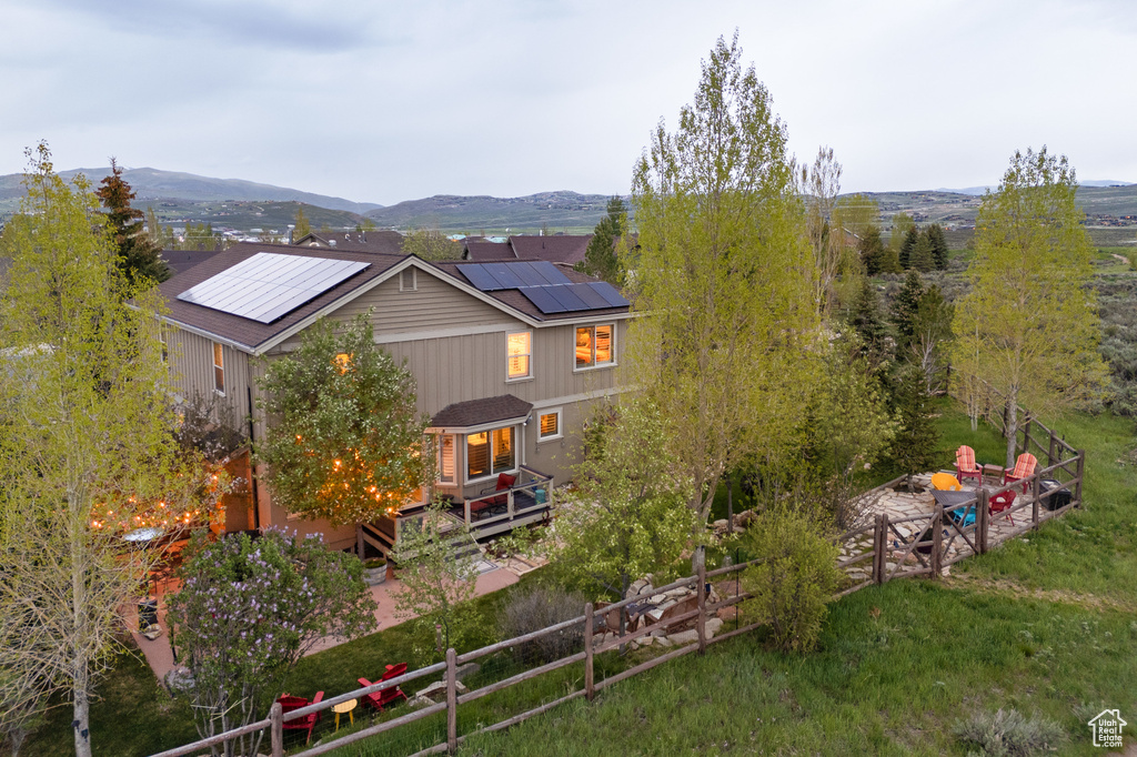 Rear view of property with roof mounted solar panels and a deck with mountain view