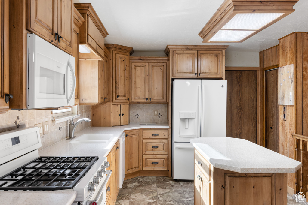 Kitchen featuring white appliances, a sink, tasteful backsplash, and a kitchen island