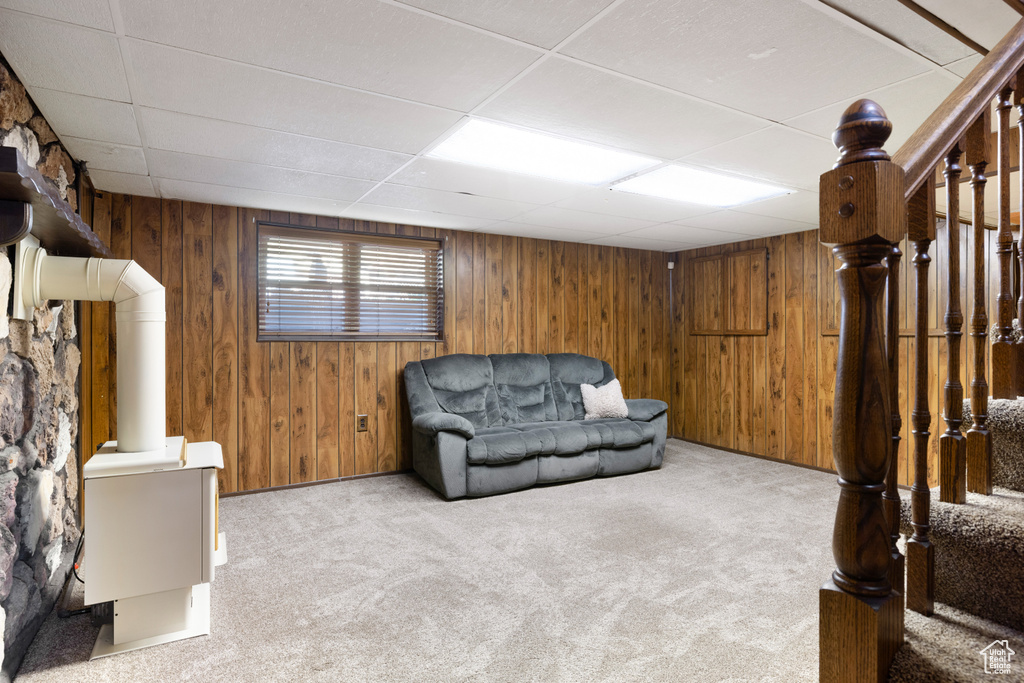 Sitting room featuring carpet flooring, a drop ceiling, and wood walls