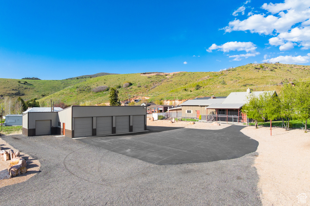 View of front facade with a mountain view, a residential view, community garages, and an outdoor structure