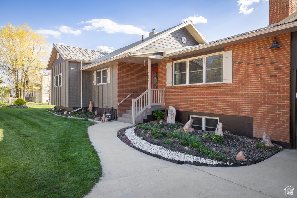 View of front facade featuring a front lawn, a chimney, and brick siding