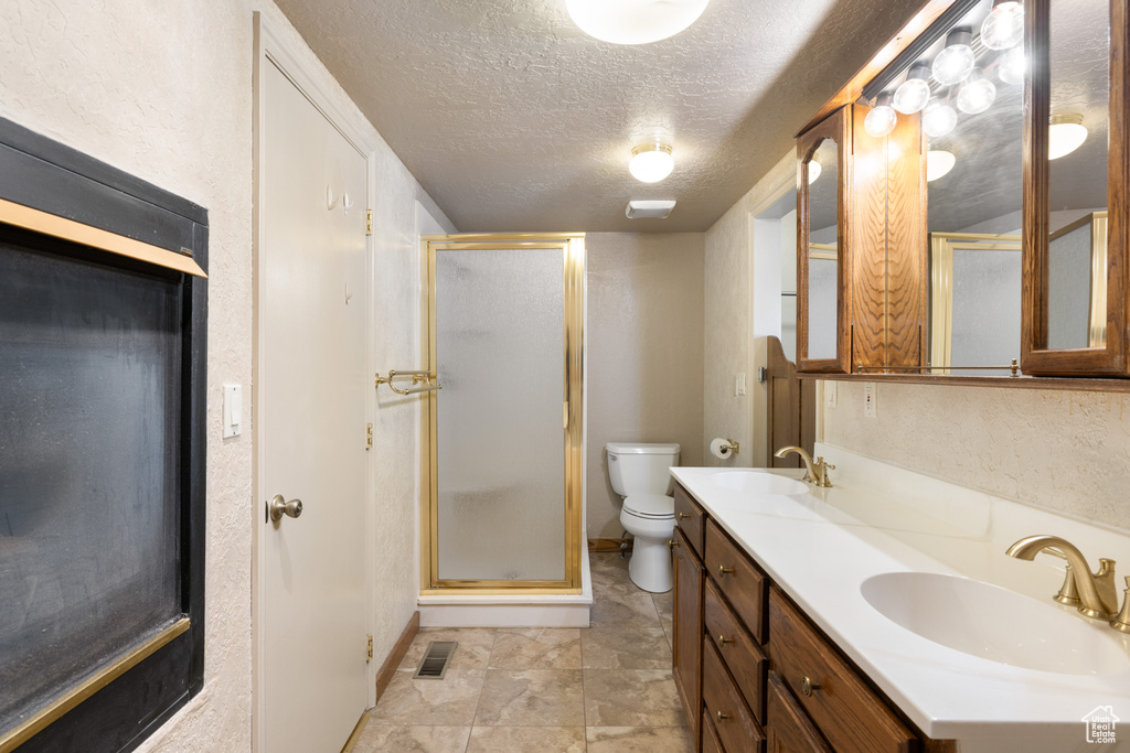Full bathroom featuring a stall shower, toilet, a textured ceiling, and baseboards