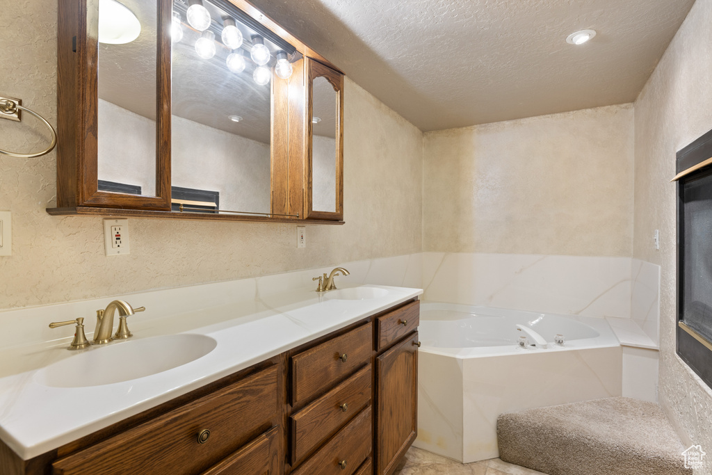 Full bathroom featuring a textured ceiling, a textured wall, a garden tub, and double vanity