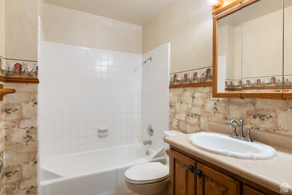 Bathroom with shower / tub combination, toilet, vanity, and tasteful backsplash