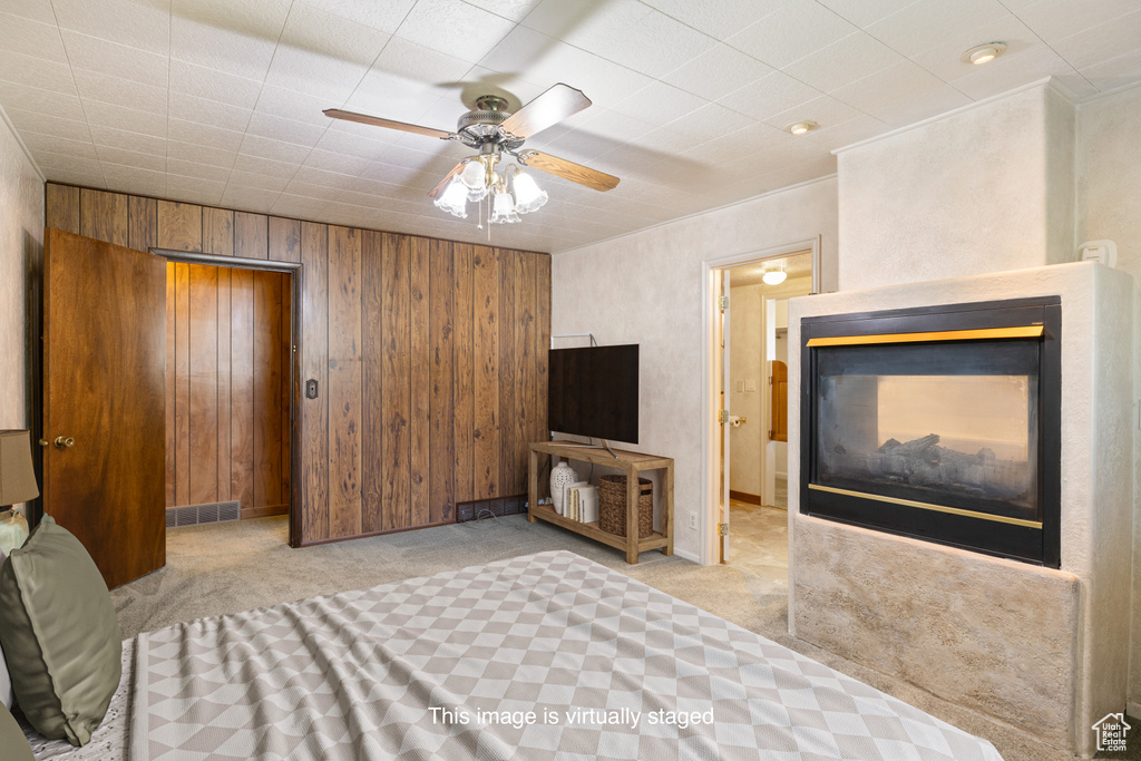 Unfurnished bedroom with carpet floors, wood walls, and a ceiling fan