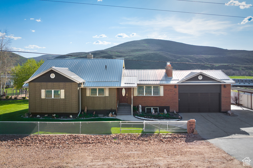 Ranch-style house featuring a mountain view, a fenced front yard, and a garage