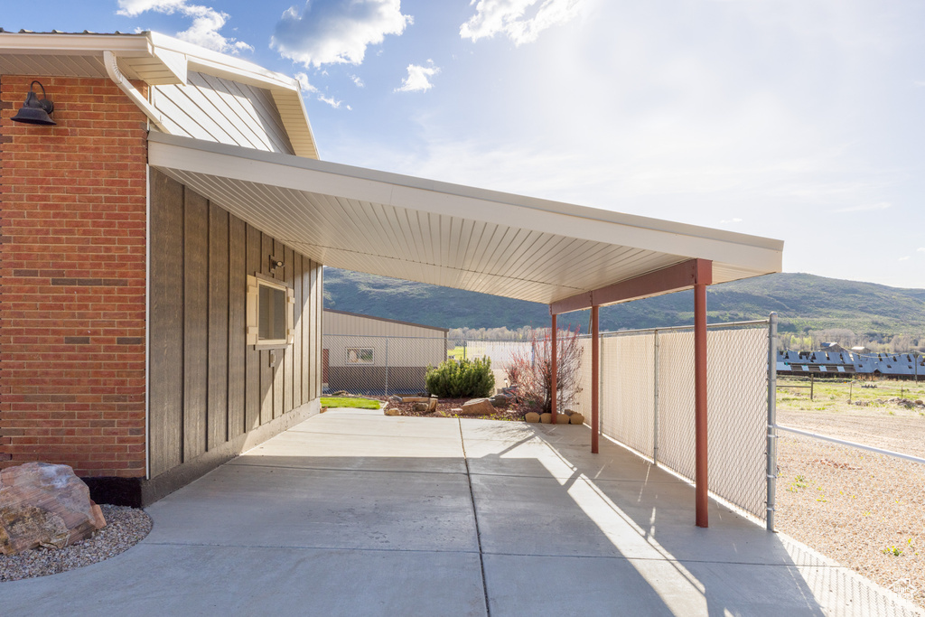 View of patio / terrace with fence, a carport, concrete driveway, and a mountain view