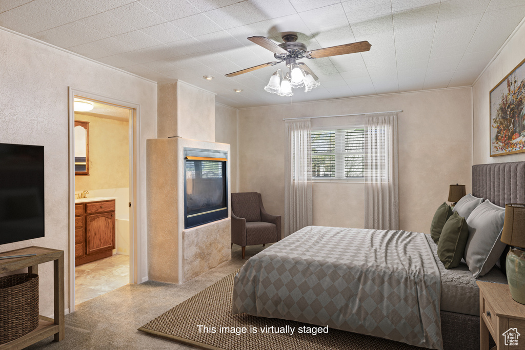 Bedroom with ceiling fan, a glass covered fireplace, crown molding, and connected bathroom