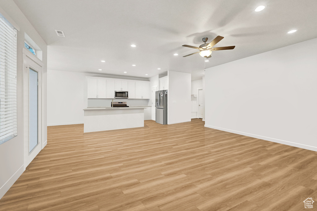 Unfurnished living room with light wood-style flooring, ceiling fan, recessed lighting, and baseboards