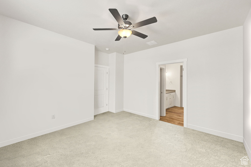 Unfurnished bedroom featuring light carpet, baseboards, connected bathroom, and ceiling fan
