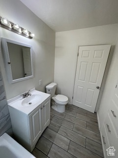 Bathroom with vanity, toilet, and a tub to relax in