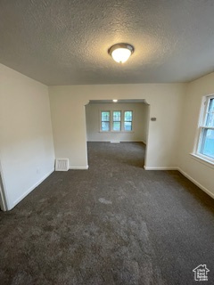 Unfurnished room with a textured ceiling, baseboards, and carpet floors