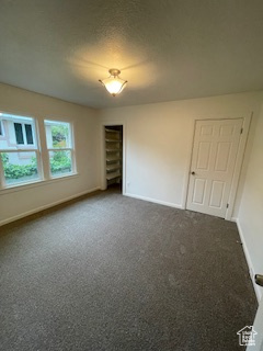 Empty room with baseboards and dark colored carpet