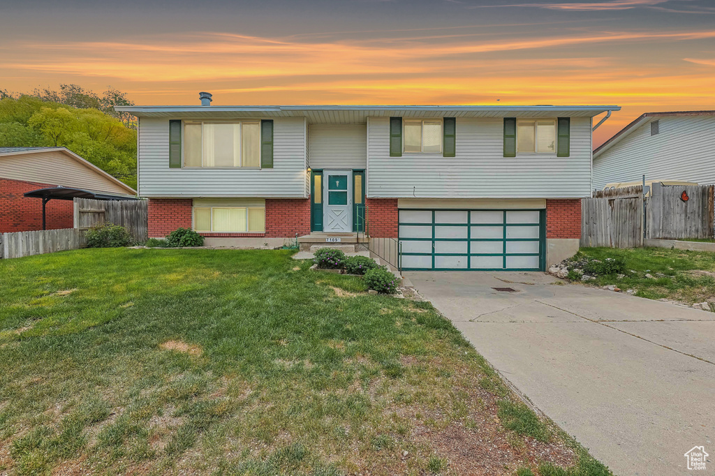 Bi-level home with brick siding, an attached garage, and concrete driveway