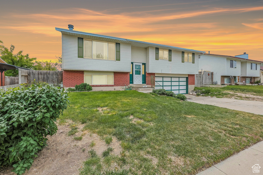 Bi-level home with brick siding, a garage, and concrete driveway