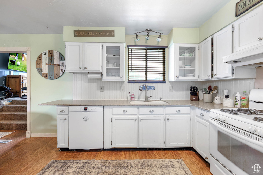 Kitchen with white appliances, a sink, under cabinet range hood, and white cabinetry