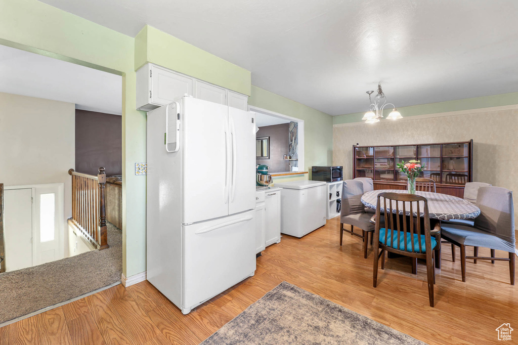 Kitchen featuring freestanding refrigerator, a chandelier, white cabinetry, light wood finished floors, and refrigerator