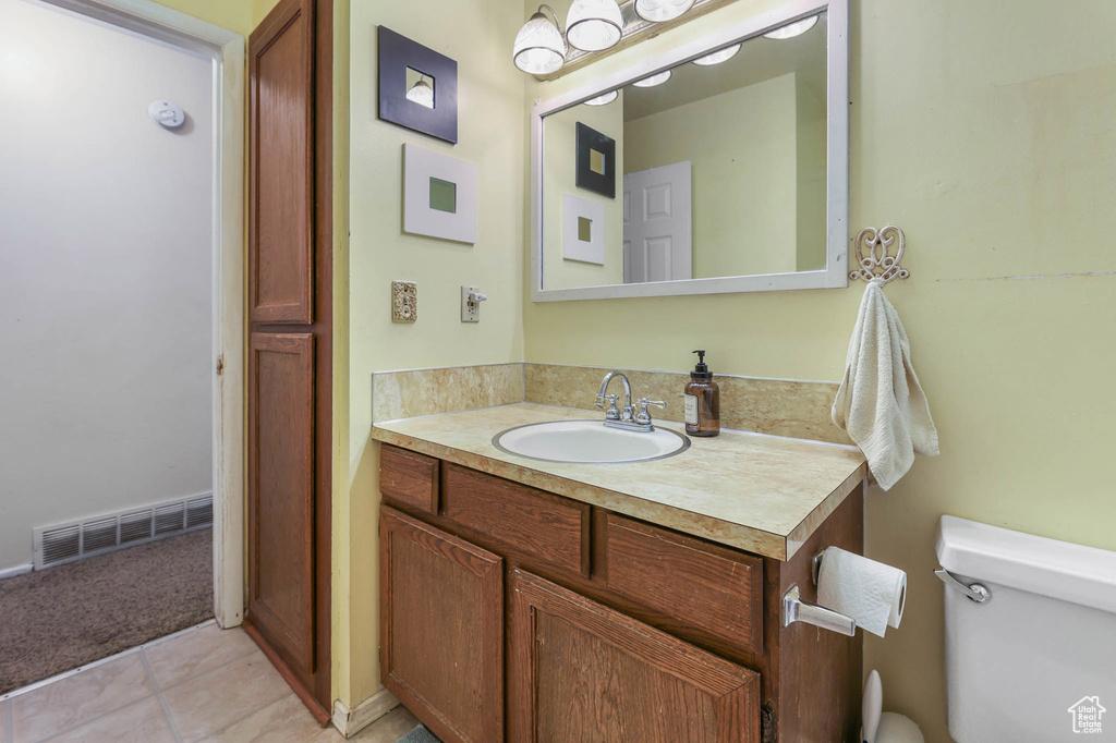 Half bathroom with toilet, vanity, and tile patterned floors
