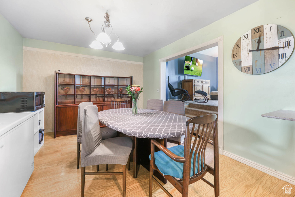 Dining room featuring light wood-type flooring, baseboards, and a chandelier
