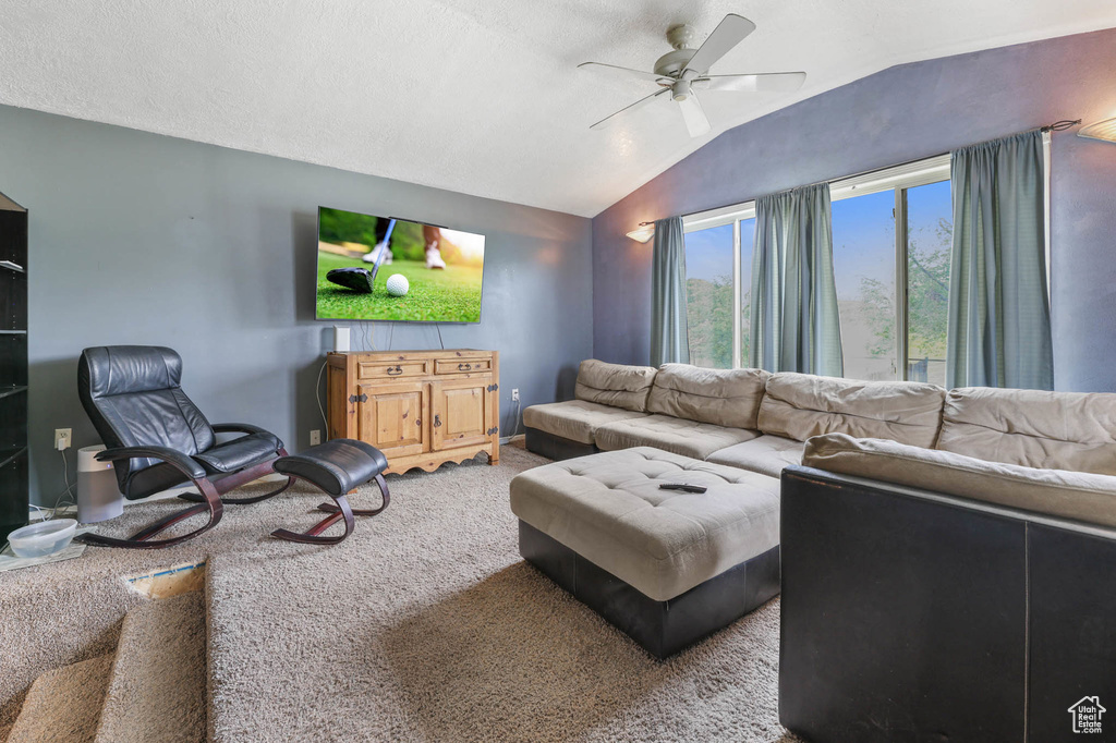 Carpeted living area featuring vaulted ceiling and ceiling fan