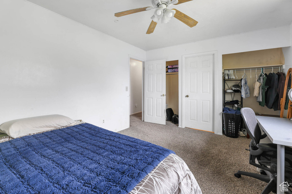 Carpeted bedroom with a desk, a ceiling fan, and a closet