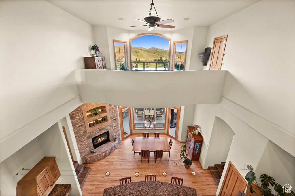 Living room with ceiling fan, a brick fireplace, wood finished floors, and a chandelier
